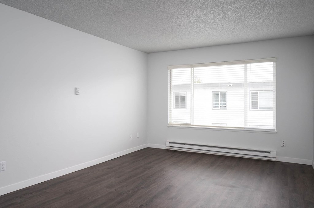 an empty living room with white walls and a window
